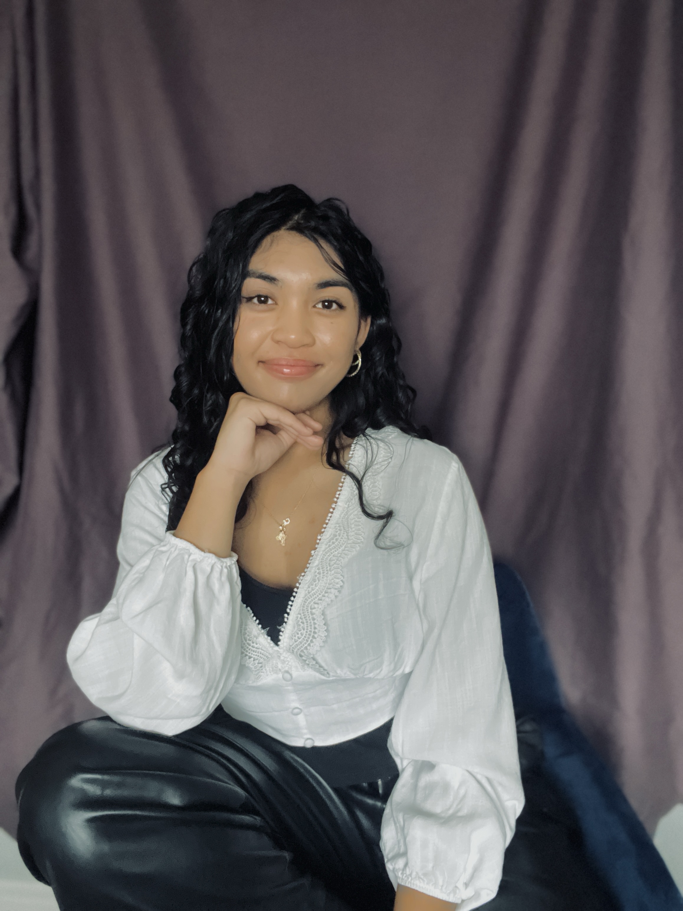 Artist portrait smiling in front of a mauve curtain