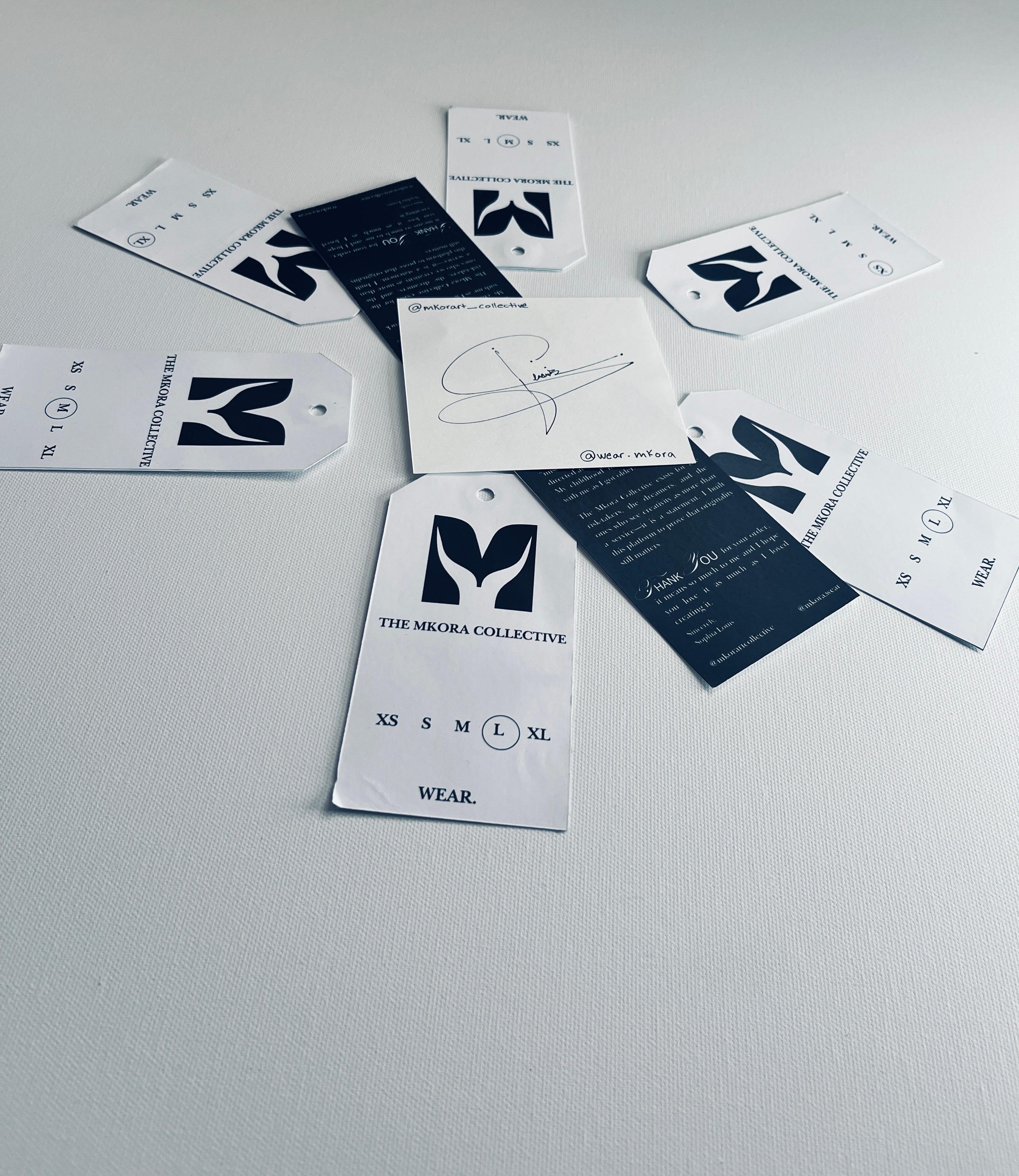 Mkora garment tags and brand cards arranged on fabric